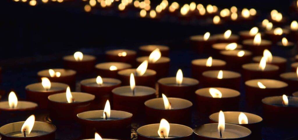 A Row Of Lit Candles In The Dark
